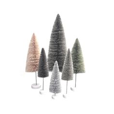 five different colored trees on white pedestals in the shape of christmas trees, all standing upright