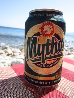 a can of beer sitting on top of a table next to the ocean