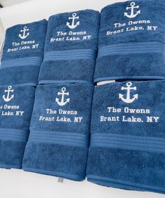 blue towels with white anchors and the names of different towns are on display in a store