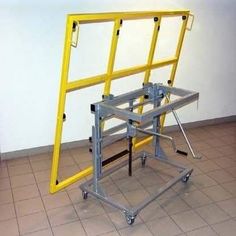 a yellow metal frame sitting on top of a floor next to a white wall and tiled floor