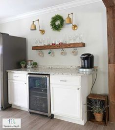 a kitchen with an oven, refrigerator and wine glasses on the shelf above it is decorated with wreaths