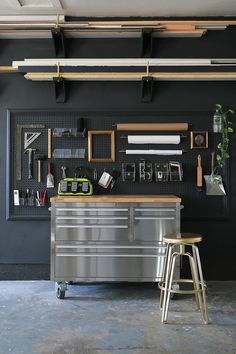 an industrial style kitchen with black walls and metal workbench in the center, along with various framed pictures on the wall