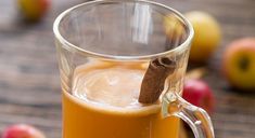 a glass mug filled with apple cider and cinnamon stick