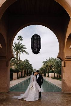 a bride and groom standing under an archway at the entrance to their wedding venue in palm trees