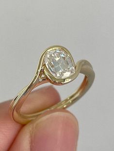 a hand holding a yellow gold ring with a white diamond