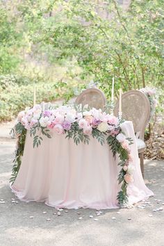 a table with flowers and candles is set up in the middle of a forest for a wedding reception