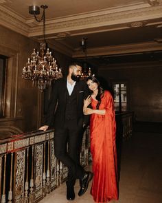 a man and woman standing next to each other in front of a chandelier