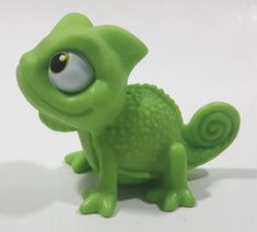 a green toy with big eyes sitting on a white surface