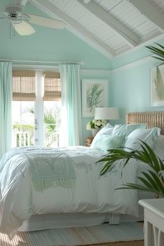 a bed sitting under a window in a bedroom next to a ceiling fan and windows