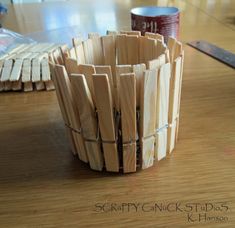 a cup made out of wooden sticks sitting on top of a table next to a can