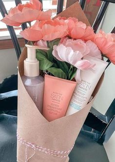 a bouquet of flowers in a brown paper bag with some skin care products on it