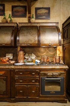 an old fashioned kitchen with copper pots and pans on the stove top, along with wooden cabinets