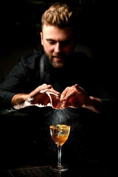 a man sitting at a table in front of a glass filled with liquid and sprinkles