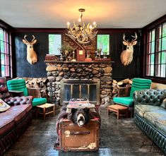 a living room with couches, chairs and a fire place in the center surrounded by deer heads