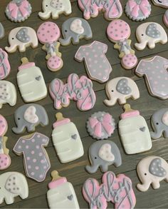 baby shower cookies with pink and gray decorations on a wooden table in the shape of elephants