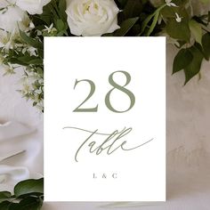 a table number with white flowers and greenery