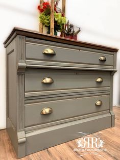 a gray dresser with brass handles and knobs on the bottom drawer, in front of a mirror