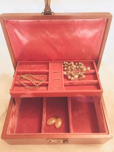 an open red suitcase with jewelry in it