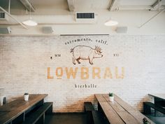 the restaurant is decorated with wood tables and benches, along with a brick wall that says lowbrail