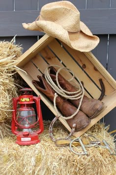 a wooden box with cowboy hats and other items in it on top of hay bales