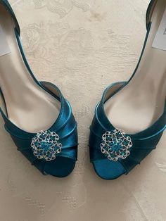 a pair of blue high heeled shoes with jewel embellishments on the toes