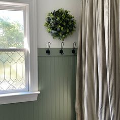 a bathroom with green and white walls, striped shower curtain, and a round wreath on the wall