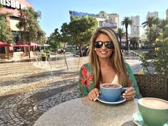 a woman sitting at a table with a cup of coffee