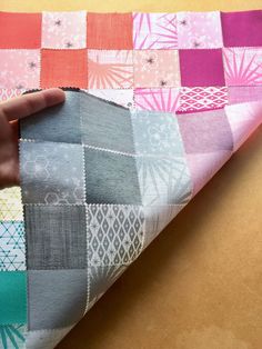 a person is holding onto a patchwork piece of fabric that has been made into a quilt