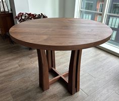 a wooden table sitting in front of a window on top of a hard wood floor