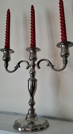 three red candles sitting on top of a silver candelabra