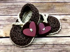 two crocheted baby shoes with hearts on them