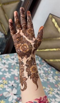 a woman's hand with henna tattoos on it and flowers all over the arm