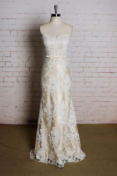 a wedding dress on display in front of a brick wall