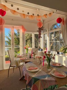 a dining room table set with plates and paper lanterns hanging from the ceiling above it