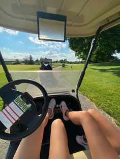 a person sitting in the driver's seat of a golf cart with their feet on the steering wheel