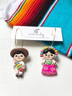 two little mexican dolls are hanging from earrings