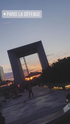 people are walking around in front of a large building at sunset with the words paris la defense on it