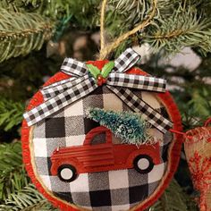 an ornament hanging from a christmas tree decorated with plaid fabric and a red truck