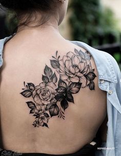 the back of a woman's shoulder with flowers and leaves tattooed on her upper