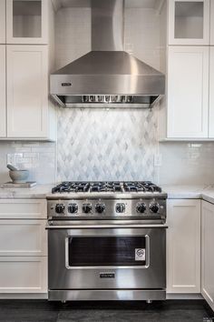 a stove top oven sitting inside of a kitchen next to white cabinets and counter tops