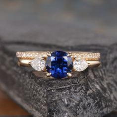 a blue and white diamond ring sitting on top of a rock