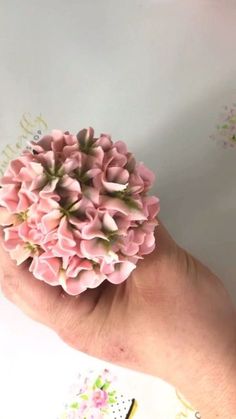 a hand holding a small pink flower in it's palm