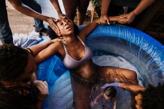 a woman in a bathing suit is sitting in a pool with other people around her