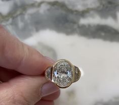 a close up of a person's hand holding a ring with a diamond in it