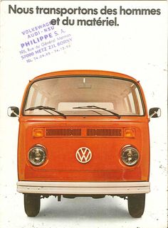 an orange vw bus parked in front of a white wall with writing on it