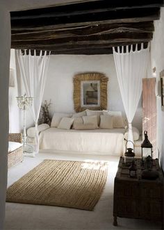 a bedroom with white bedding and curtains