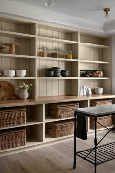 a room with many shelves and baskets on the wall next to a table in front of it