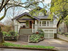 a house with green siding and trees in the front yard