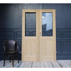 an empty chair sitting in front of two wooden doors with glass panes on them