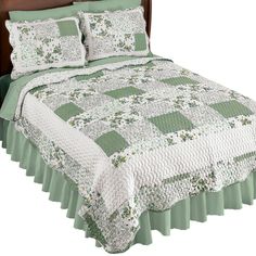 a green and white quilted bedspread on a bed with matching pillow cases